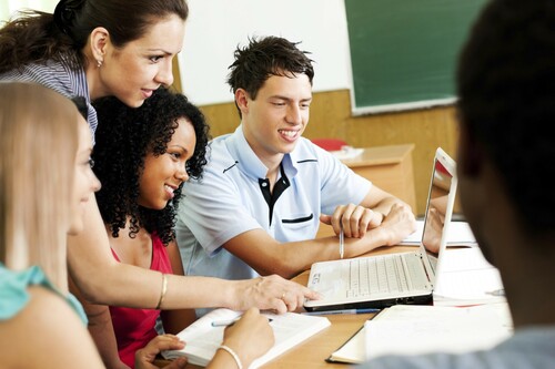 Teacher and students working at laptop