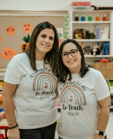two women standing together smiling at the camera with shirts that say 